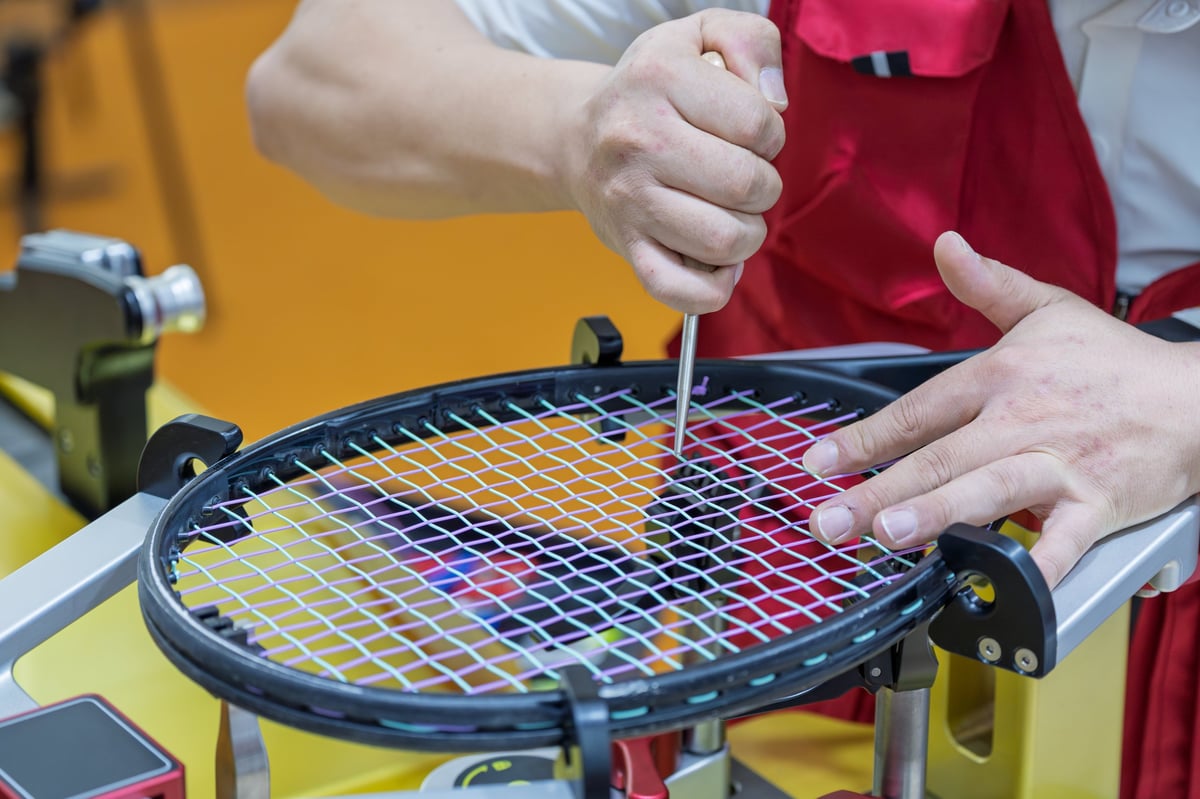 Skilled craftsman performing professional stringing work on a tennis racket