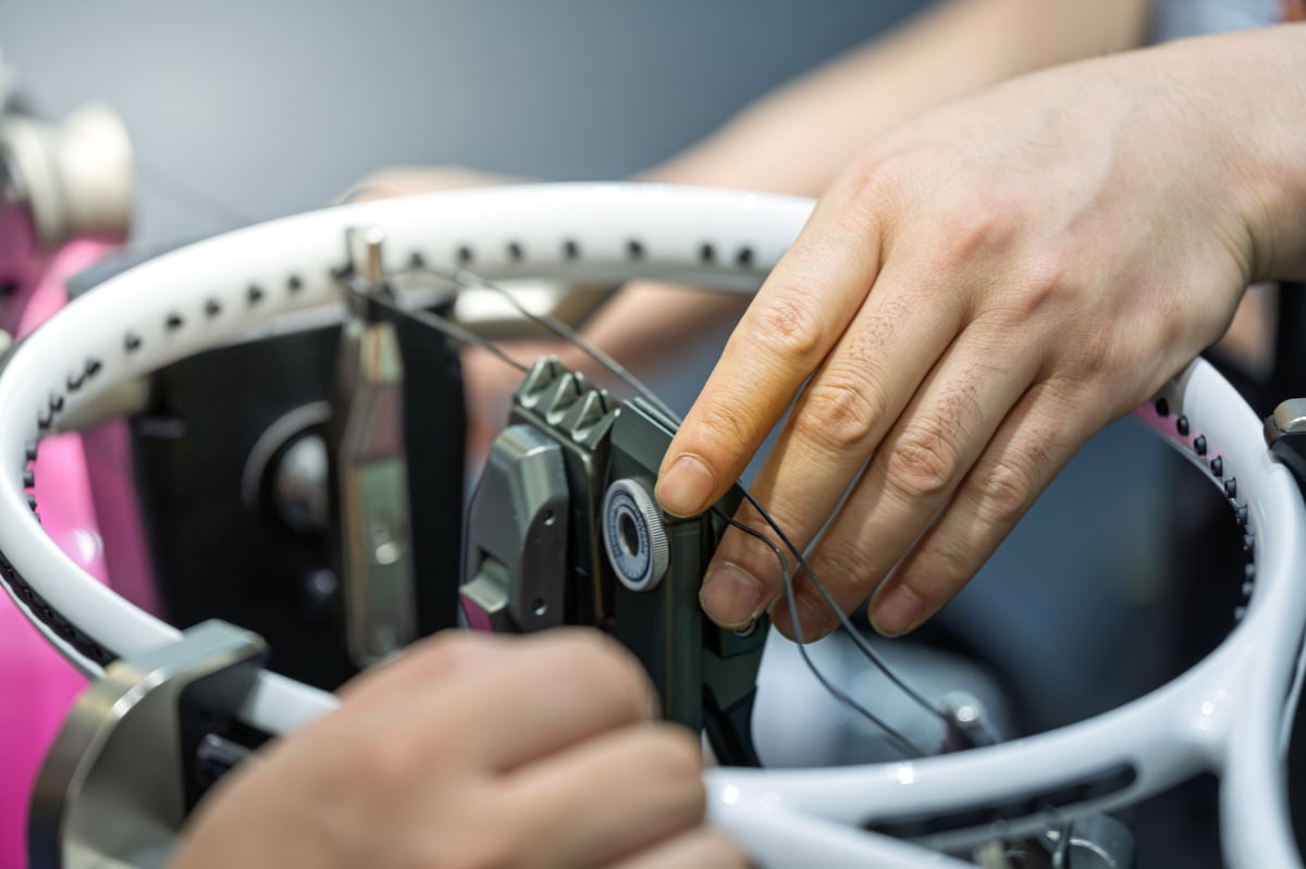Skilled technician operating professional equipment to string a tennis racket