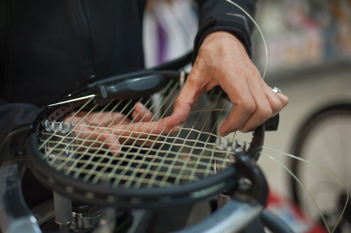 Close up of a stringer's hands doing precise racket stringing in the workshop